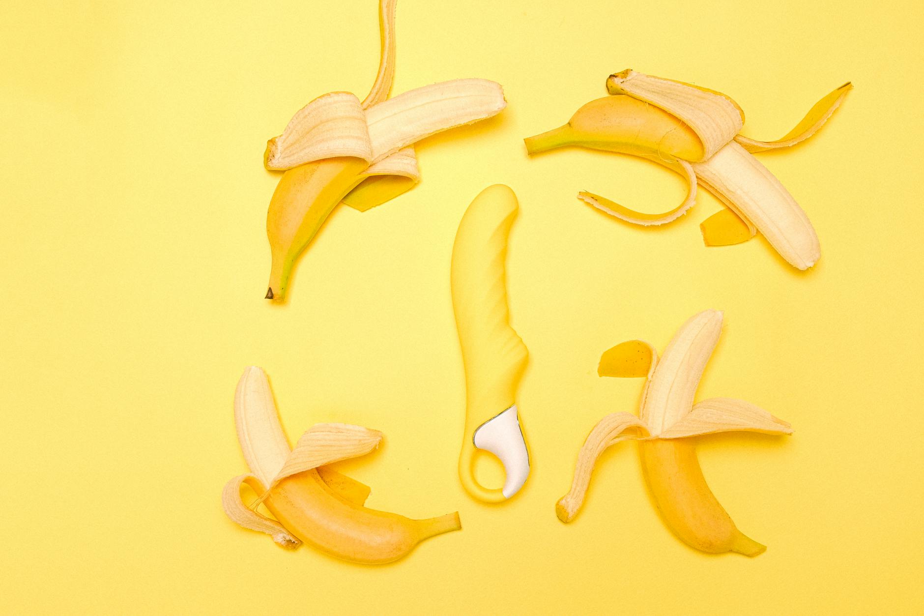 O mână care ține un vibrator portocaliu într-un cadru minimalist.