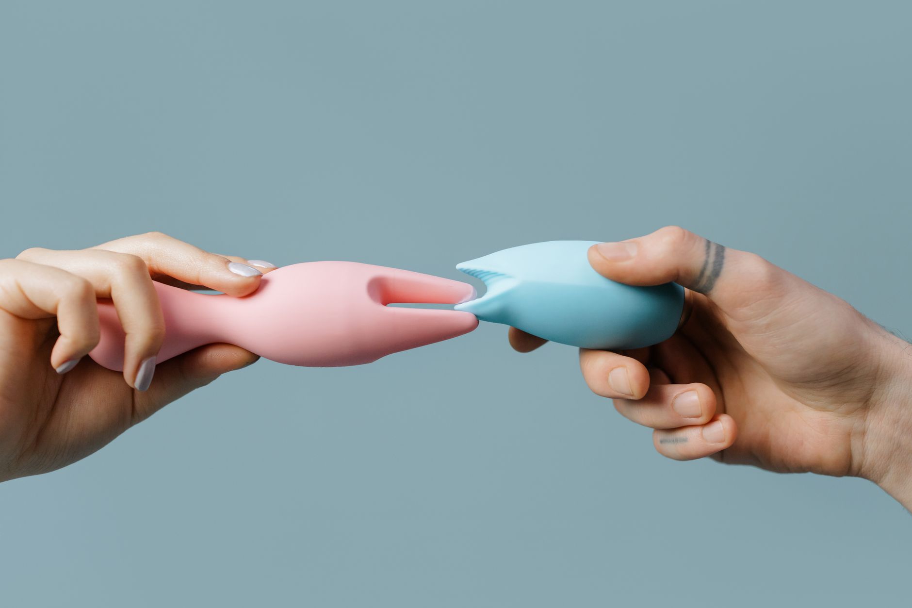Mână ținând un vibrator de culoare portocalie pe fundal minimalist, reprezentând revenirea sexuală post-chirurgicală