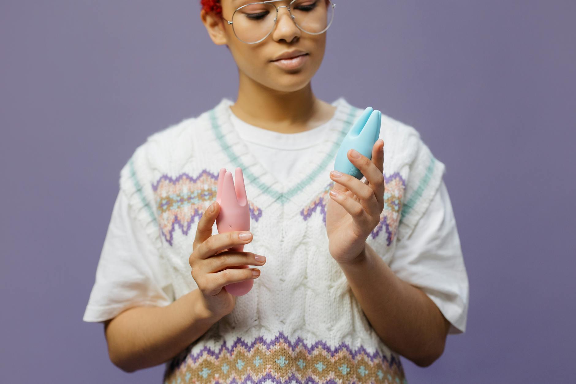 Femeie cu ochelari ținând în mână vibratoare colorate, într-o poziție meditativă și contemplativă.