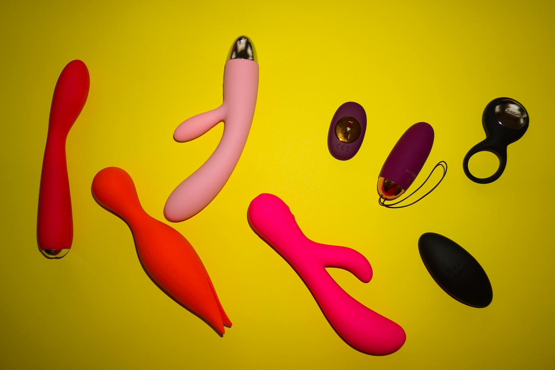 Femeie care ține un vibrator roz într-un cadru plin de cărți, reprezentând redescoperirea intimității și plăcerii